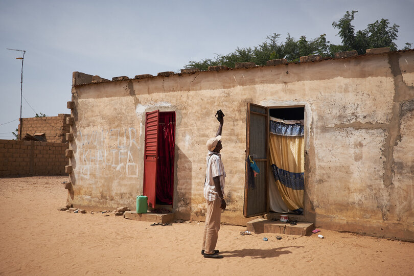 A grader holds up a mobile phone with the Tropical Data application to capture GPS coordinates during a trachoma survey in Senegal.