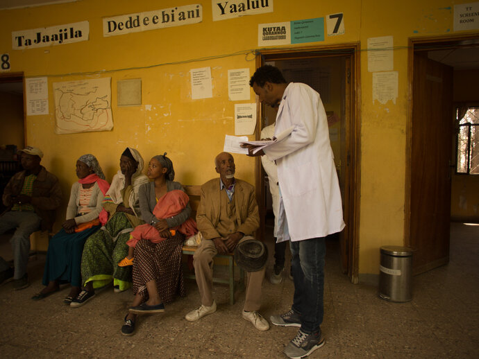 A healthworker stands in the middle of a clinic. 