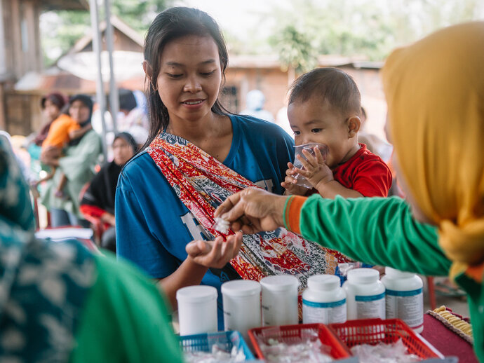 A woman and child receive medicine during an MDA in Indonesia