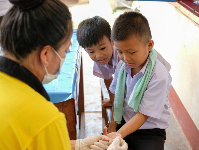 A young boy has his finger pricked during a survey for lymphatic filariasis. 