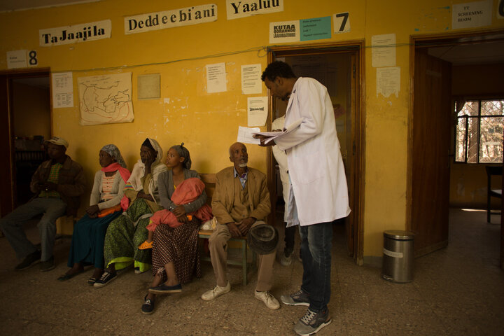 A healthworker stands in the middle of a clinic. 