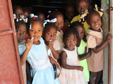 Haitian schoolchildren gather by the door during an NTD survey. 