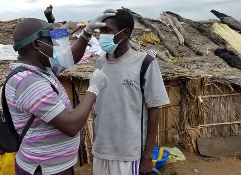 A surveyor in DRC uses the loupe-shield to examine a man's eyes for trachoma.