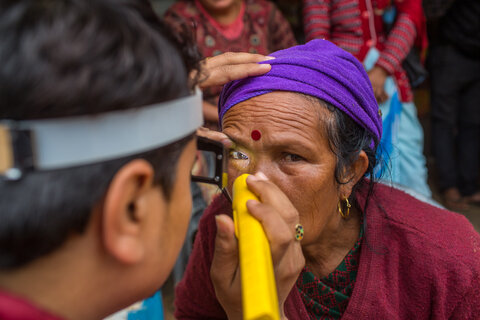 A trained grader from NNJS checks the eyes of a woman for clinical signs of trachoma during one of the last surveys before Nepal achieved validation of elimination of trachoma in 2018. Photo by Nabin Baral for RTI International