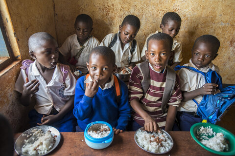 Children receive rice and beans prior to taking medicines at their school.