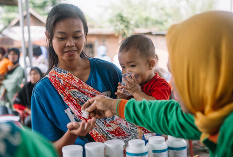 A woman and child receive medicine during an MDA in Indonesia