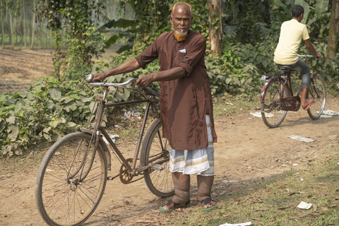 Mohim Uddin rides his bicycle to a health care visit to discuss lymphedema care with community health providers. After many years, he’s finally receiving the care he needs to become more mobile. Photo credit: RTI International/ Abir Abdullah